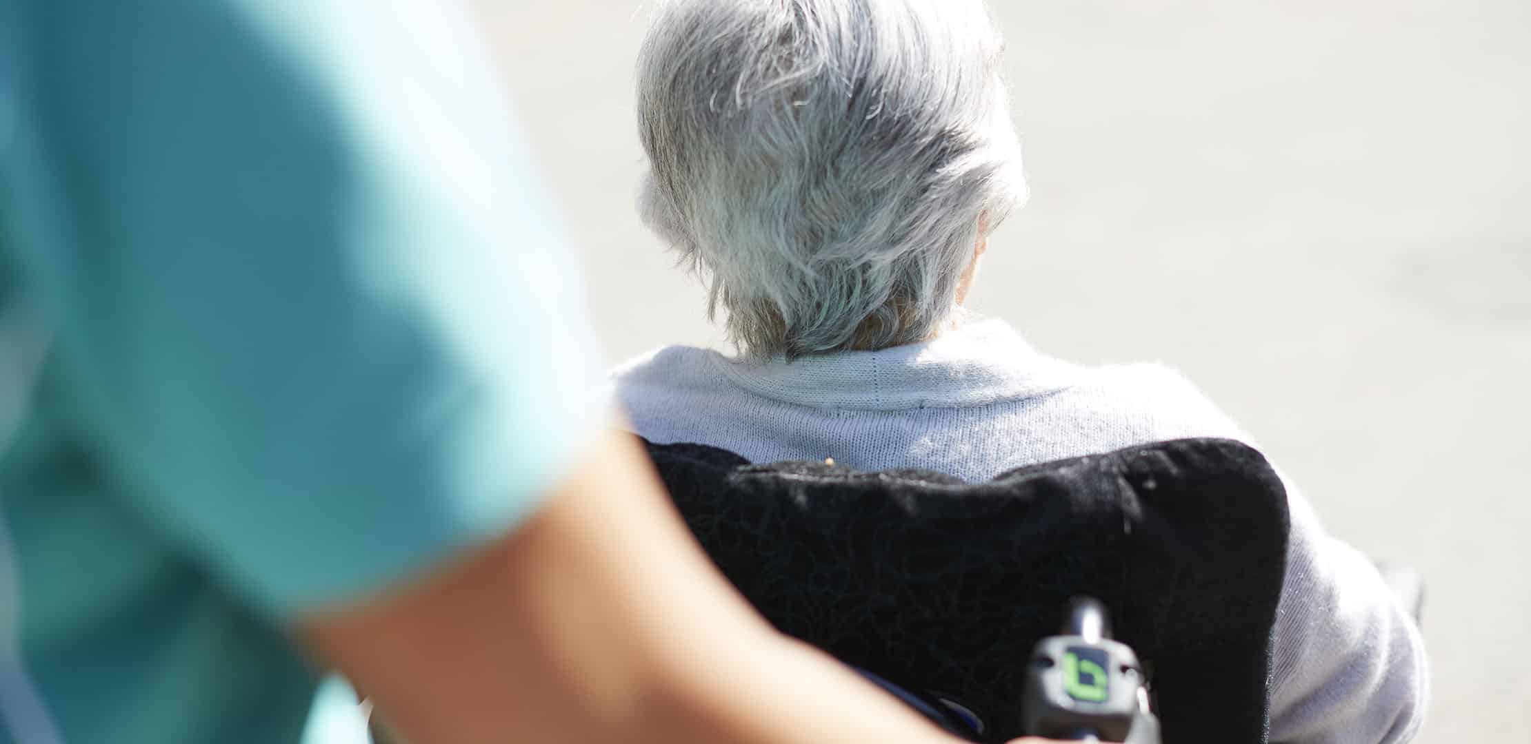 En person ses köra en äldre kvinna som sitter i rullstol